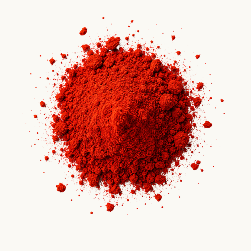 A mound of bright red powder of Astaxanthin with fine particles scattered around it on a plain white background. 