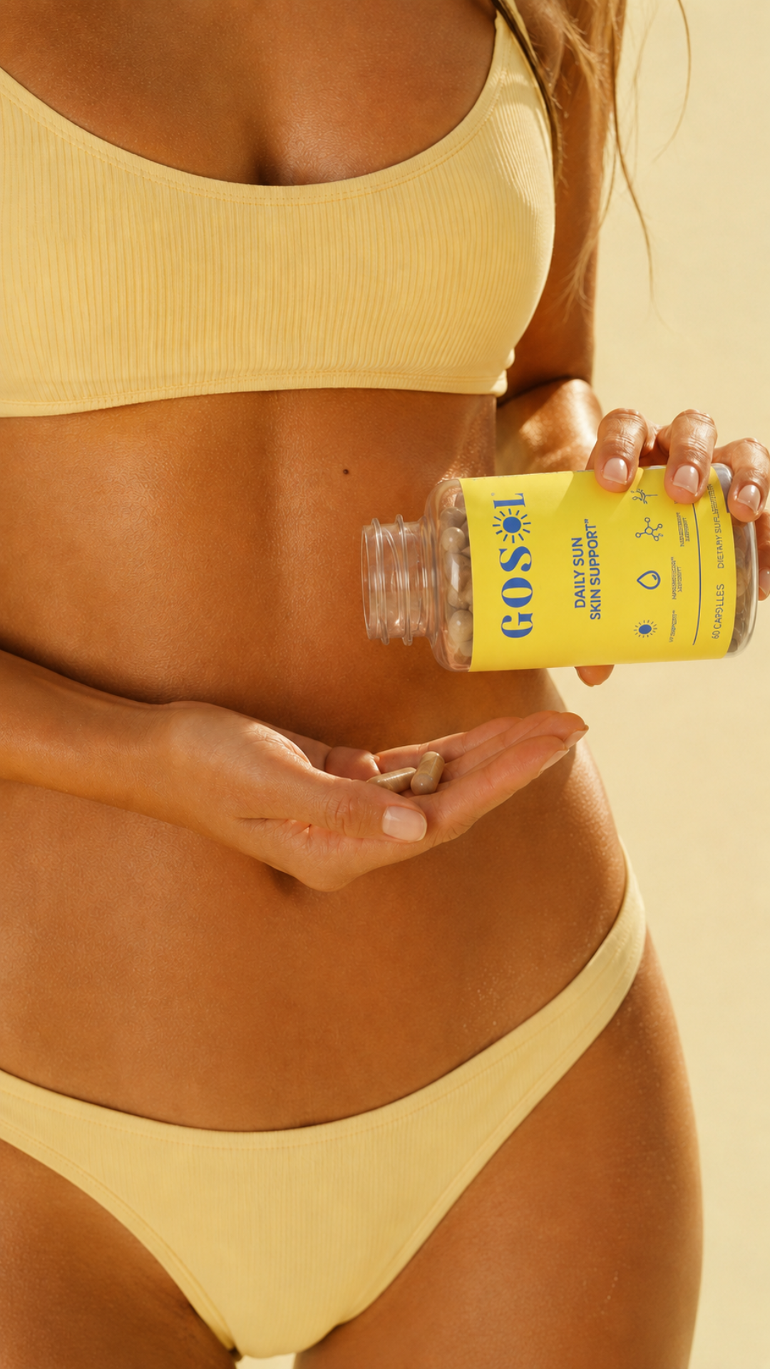 A woman in a pale yellow ribbed bikini holds a clear bottle labeled GoSol and pours capsules into her hand against a warm beige background.