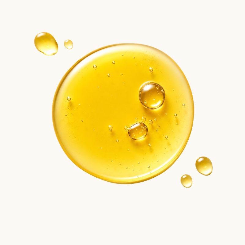 A glossy, translucent droplet of golden yellow vitamin E oil on a clean off-white background, with a few smaller droplets scattered nearby.